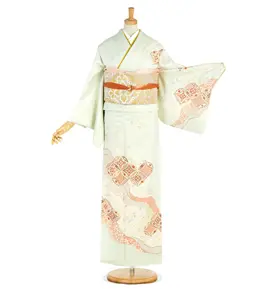 淡い桃色と褐色の模様が入った伝統的な白い着物を着たマネキン。着物は長い袖と、精巧な模様の帯が特徴です。マネキンは片腕を上げて袖を見せているポーズをとっています。.