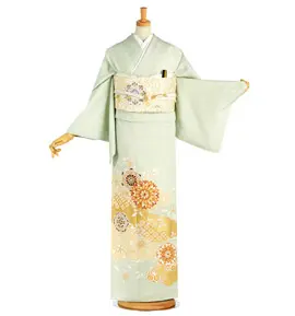マネキンに飾られた着物。淡い緑色に、白、クリーム、オレンジの花柄が描かれている。袖は長く、華やかな帯で締められている。.