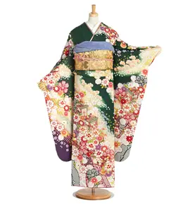 マネキンが、濃い緑の背景に赤、黄、白の花柄が描かれた日本の伝統的な着物を着ています。着物は袖が広く、金色の帯が特徴で、自然の要素と精巧なディテールが織り込まれたデザインです。.