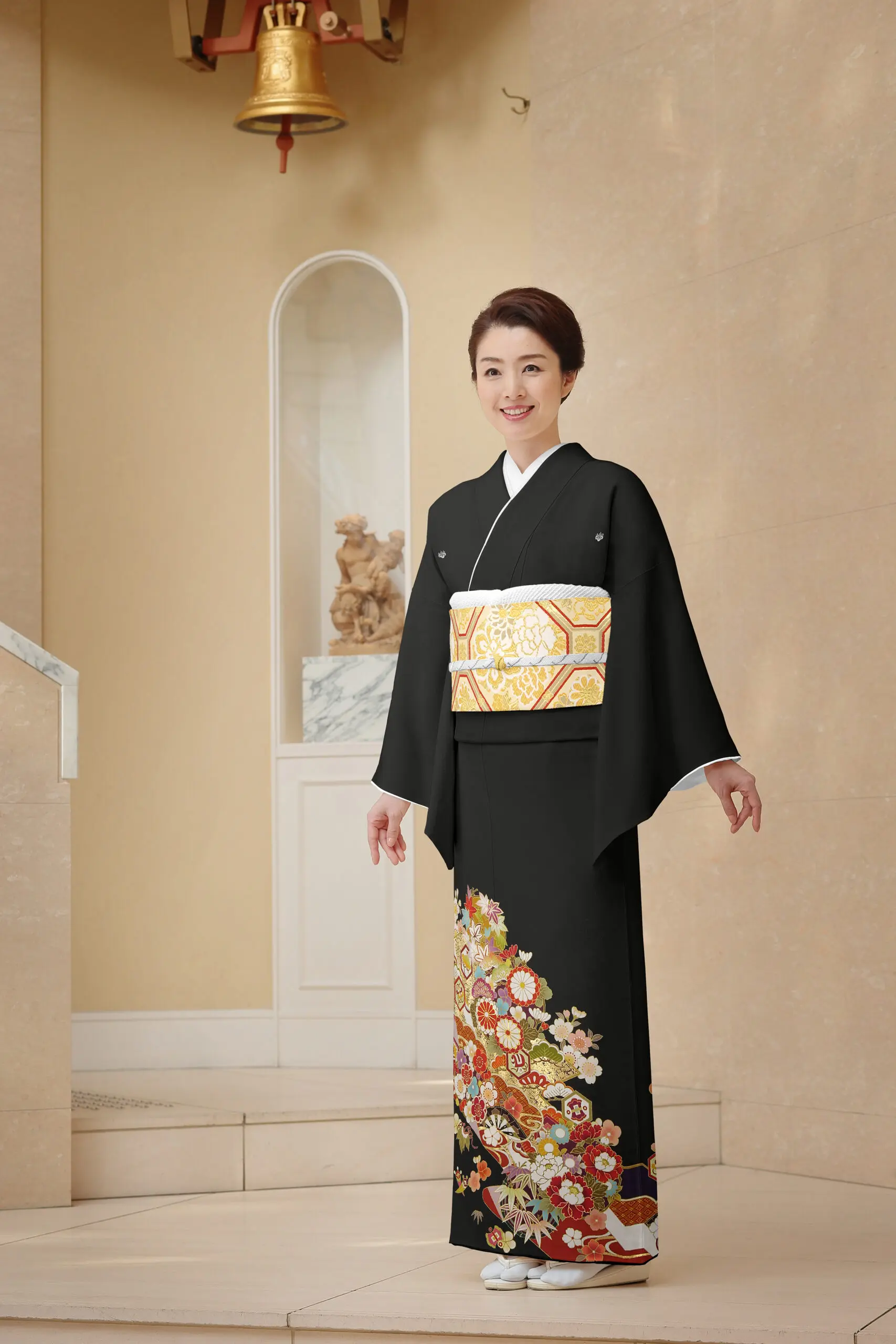 黒留袖No.102 MOサイズ（ヒップ115cm）。カラフルな花柄と金と白の帯。背景に飾られた床の間と鐘。.